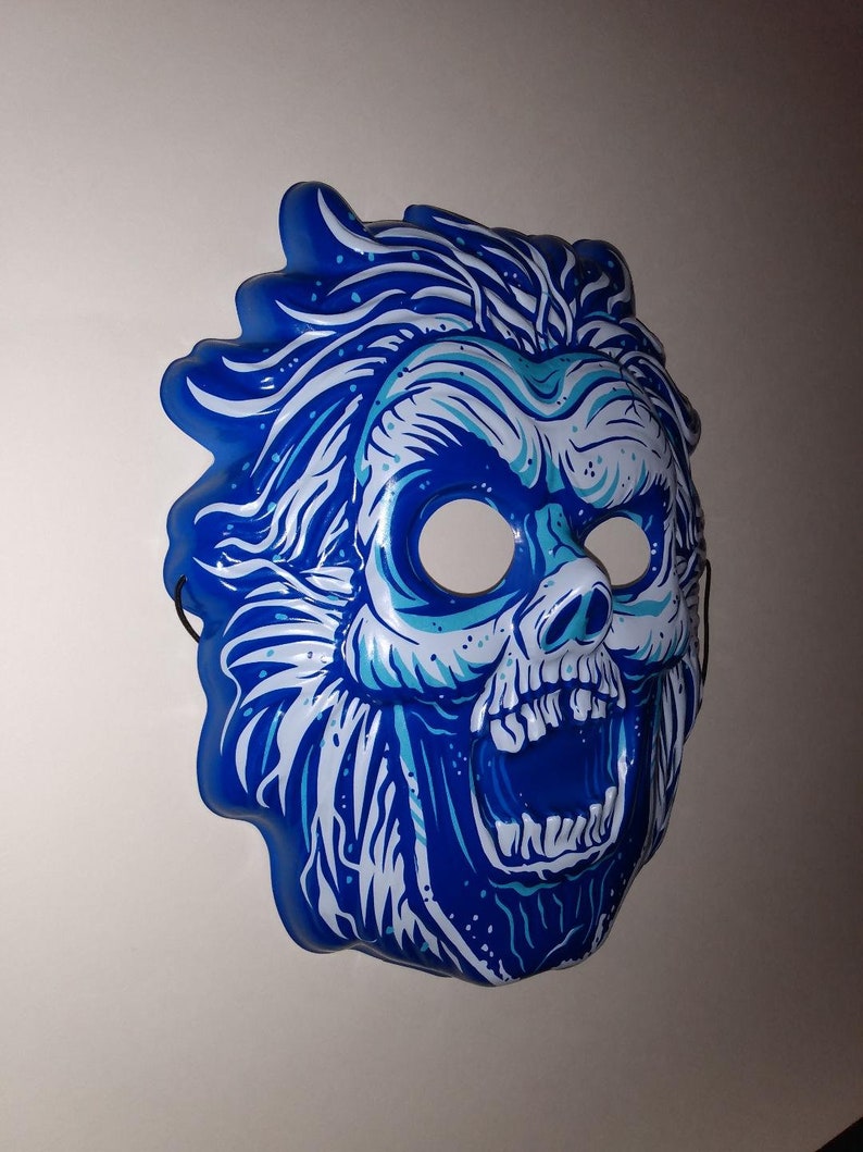 May include: A blue and white plastic Halloween mask of a skull with a wide open mouth and a wild, spiky hair design.