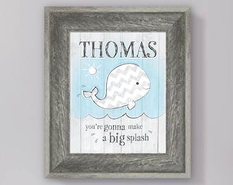 May include: A framed print with a light blue background and a white whale with a gray chevron pattern. The whale is jumping out of the water and the text "THOMAS you're gonna make a big splash" is below the whale.