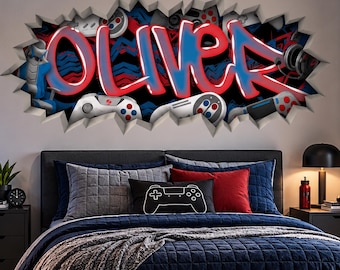 May include: A wall decal featuring the name OLIVER in red and blue graffiti-style lettering, surrounded by a 3D-effect cracked wall design with gaming controllers and headsets, set above a bed with navy blue bedding and a black gaming controller pillow.