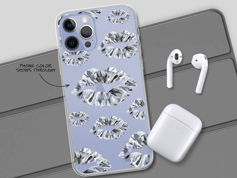 May include: A clear phone case featuring a design of silver glitter lips on a light purple background. The case is displayed on a grey surface with a pair of white wireless earbuds and a white charging case.