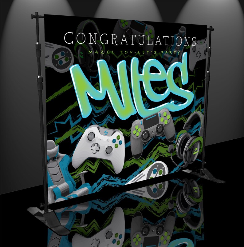 May include: A black and green gamer themed backdrop with the text "Congratulations Mazel Tov - Let's Party Miles!"  The backdrop features a variety of gaming controllers, headsets, and a gaming chair.