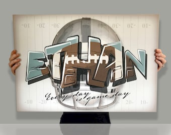 May include: A white and brown football helmet with a black face mask is centered on a white and gray background with a football field design. The word "ETHAN" is written in large, stylized letters in brown, white, and blue. The text "Every day is game day" is written in black cursive below the helmet.