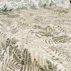 May include: A white fabric with a green fern pattern. The fabric has a subtle texture and a light, airy feel.