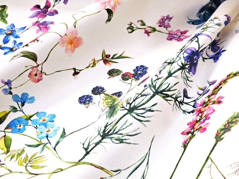May include: White fabric with a floral print featuring blue, pink, purple, and green flowers. The flowers are arranged in a random pattern and are surrounded by green leaves.
