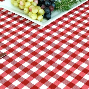 Pu&ograve; includere: Tovaglia a quadri rossi e bianchi con due posti a tavola, ognuno con un piatto bianco, un tovagliolo e una forchetta. Un piatto bianco con uva verde e viola &egrave; al centro della tovaglia.