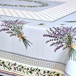 May include: A light blue tablecloth featuring lavender bouquets tied with twine. The design includes olive branches and decorative borders in green, black, and purple. The tablecloth is made of a soft, durable fabric.