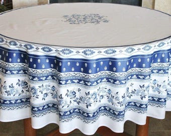 May include: A round tablecloth featuring a white center with a blue floral medallion. The border displays horizontal bands of dark blue and white with intricate floral patterns, leaf motifs, and geometric designs, creating a decorative edge.