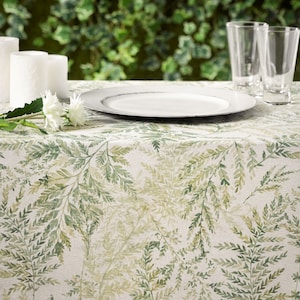 May include: A white tablecloth with a green fern pattern. A white plate and two clear glasses are on the table.