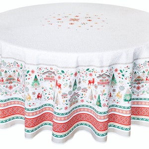 May include: White round tablecloth with a red, green, and gold winter village design. The design features houses, trees, deer, and snowflakes. The tablecloth has a scalloped edge.