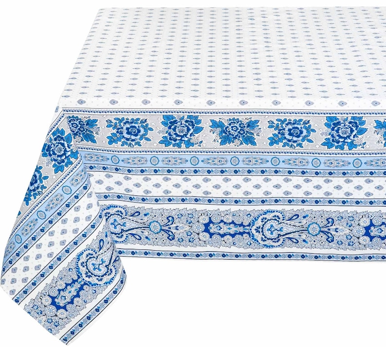 May include: A white tablecloth with a blue and white paisley pattern. The tablecloth has a border with a floral design.