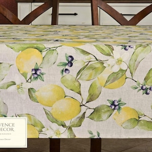 May include: A tablecloth with a watercolor lemon and floral design. The fabric features yellow lemons, green leaves, white blossoms, and purple berries. The tablecloth has the text "PROVENCE DECOR" in a white rectangle.