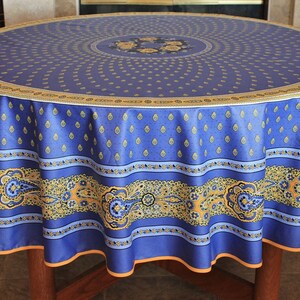 May include: A blue and gold round tablecloth with a paisley pattern. The tablecloth has a scalloped edge and is made of a durable fabric.