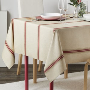 May include: A beige tablecloth with red and brown stripes. The tablecloth is laid on a wooden table with red legs. Two wine glasses and a plate are on the table.