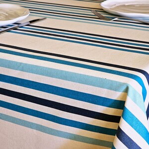 May include: A white tablecloth with blue and black stripes. The tablecloth is made of a woven fabric and has a smooth texture.