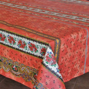 May include: A red and white tablecloth with a paisley pattern and floral border. The tablecloth is made of cotton and is perfect for a casual dining setting.