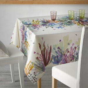 May include: A white tablecloth with a watercolor print of colorful coral and seaweed. The tablecloth is set on a table with two white chairs and glasses on the table.