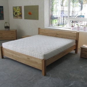 Pu&ograve; includere: Un letto con una struttura in legno e un materasso bianco. La struttura del letto &egrave; in legno massello e ha un design semplice. Il letto si trova in una camera da letto con una finestra e due comodini.