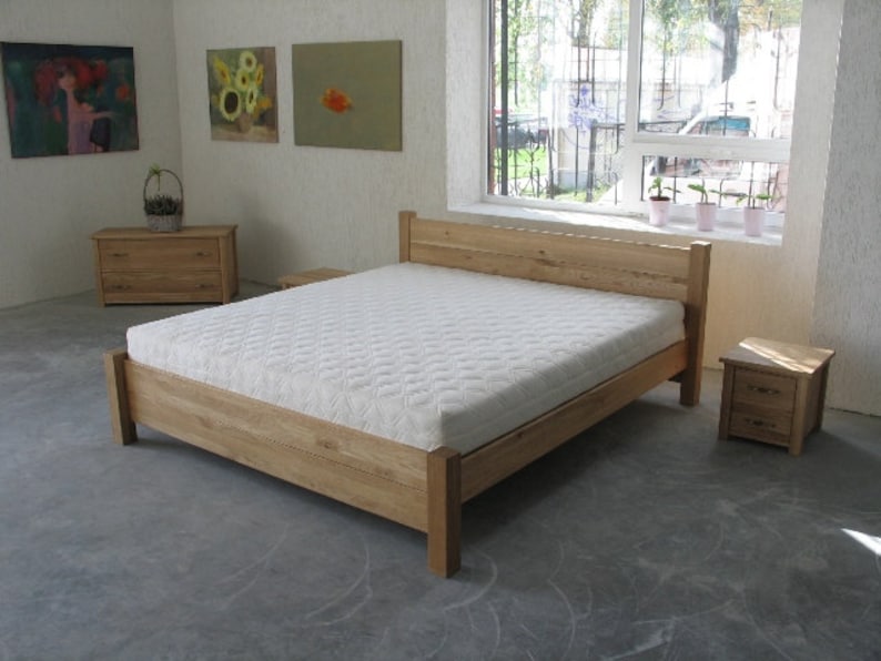 Pu&ograve; includere: Un letto con una struttura in legno e un materasso bianco. La struttura del letto &egrave; in legno massello e ha un design semplice. Il letto si trova in una camera da letto con una finestra e due comodini.