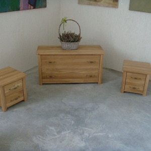 Pu&ograve; includere: Tre comodini in legno con due cassetti ciascuno. I comodini sono in legno chiaro e hanno maniglie in ottone. I comodini sono disposti in fila su un pavimento grigio chiaro.