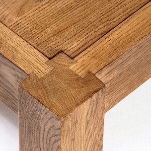 May include: Close-up of a wooden table leg with a mortise and tenon joint. The joint is made of two pieces of wood that are joined together with a groove and a tongue.