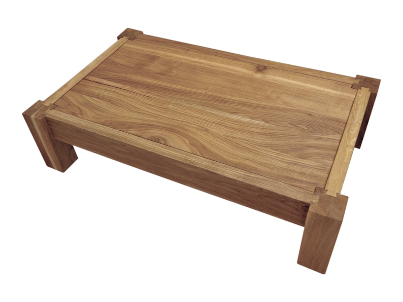 May include: A wooden coffee table with a rectangular top and four legs. The table is made of light brown wood with a natural finish.