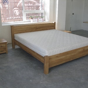 Pu&ograve; includere: Un letto con struttura in legno e un materasso bianco. La struttura del letto ha un design semplice con una testata e un piede. C'&egrave; un piccolo comodino in legno accanto al letto.