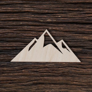 Puede incluir: Una silueta de montaña de madera blanca recortada sobre un fondo de madera marrón oscuro.