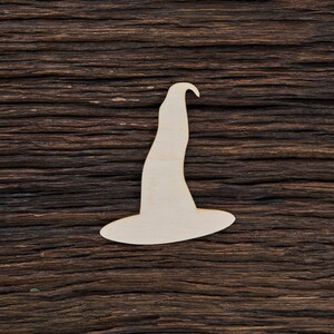 Può includere: Un ritaglio di cappello da strega in legno bianco su uno sfondo di legno marrone scuro.
