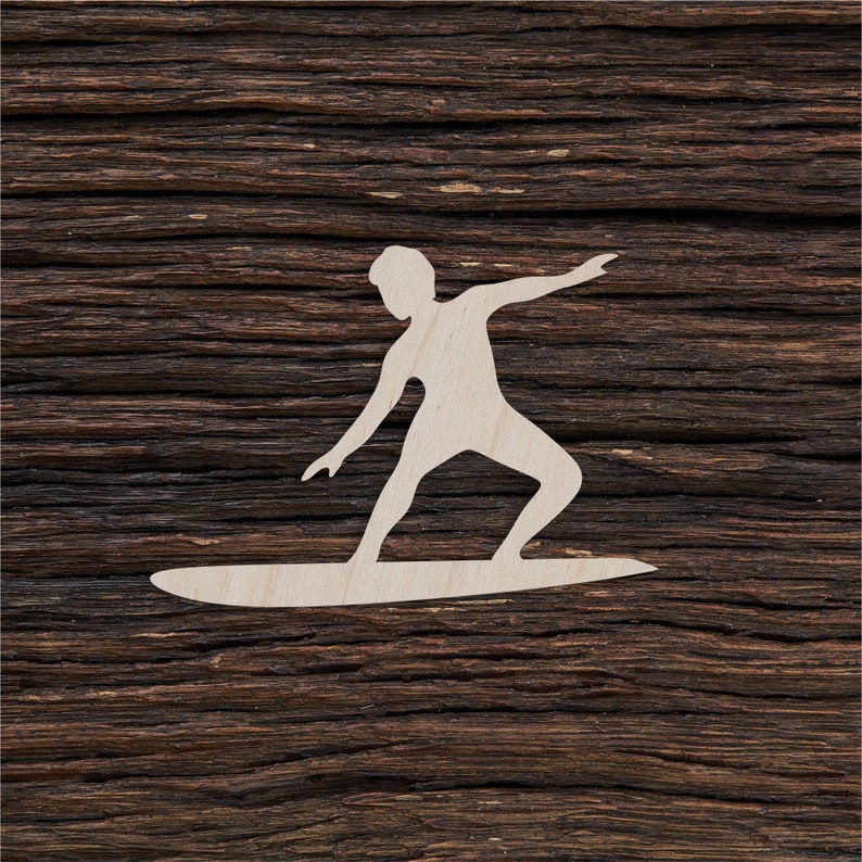 Puede incluir: Una silueta de madera blanca de una persona surfeando una ola. La silueta est&aacute; recortada de una pieza de madera y est&aacute; montada sobre un fondo de madera marr&oacute;n oscuro.