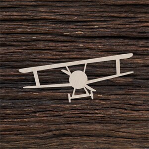 Könnte beinhalten: Ein weißer Holzausschnitt eines Vintage-Flugzeugs auf einem dunkelbraunen Holzgrund.