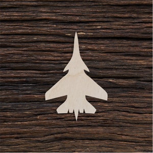 Può includere: Una silhouette bianca in legno di un aereo da combattimento su uno sfondo di legno marrone scuro.
