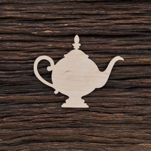 May include: A white wooden cutout of a teapot on a dark brown wooden background.