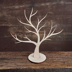 May include: A white wooden tree-shaped jewellery stand with a round base. The stand is made of wood and has a natural finish.