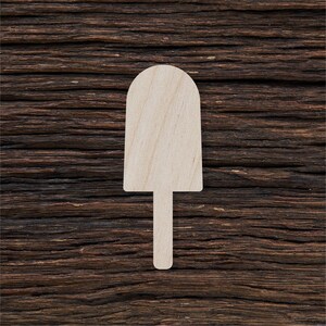 Puede incluir: Una silueta de paleta de helado de madera blanca sobre un fondo de madera marrón oscuro.