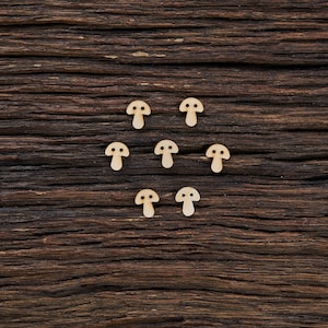 Puede incluir: Nueve botones de madera con forma de hongo dispuestos en círculo sobre una superficie de madera marrón oscura.