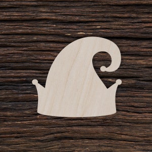 Puede incluir: Un recorte de madera de un gorro de bufón con una punta puntiaguda y un borde rizado. El gorro es de color marrón claro y tiene un diseño sencillo.