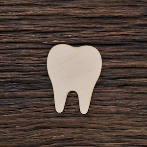 May include: A white wooden tooth cutout on a dark brown wooden background.