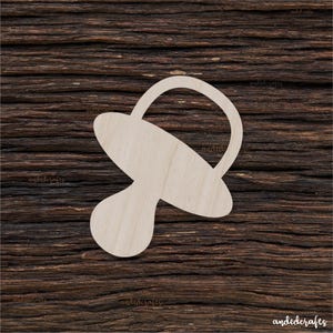 Puede incluir: Un recorte de madera de un chupete para bebé, un elemento de decoración popular para baby showers o habitaciones de bebés.