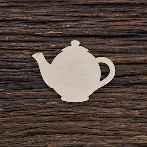 Può includere: Un ritaglio di legno di una teiera su uno sfondo di legno marrone.