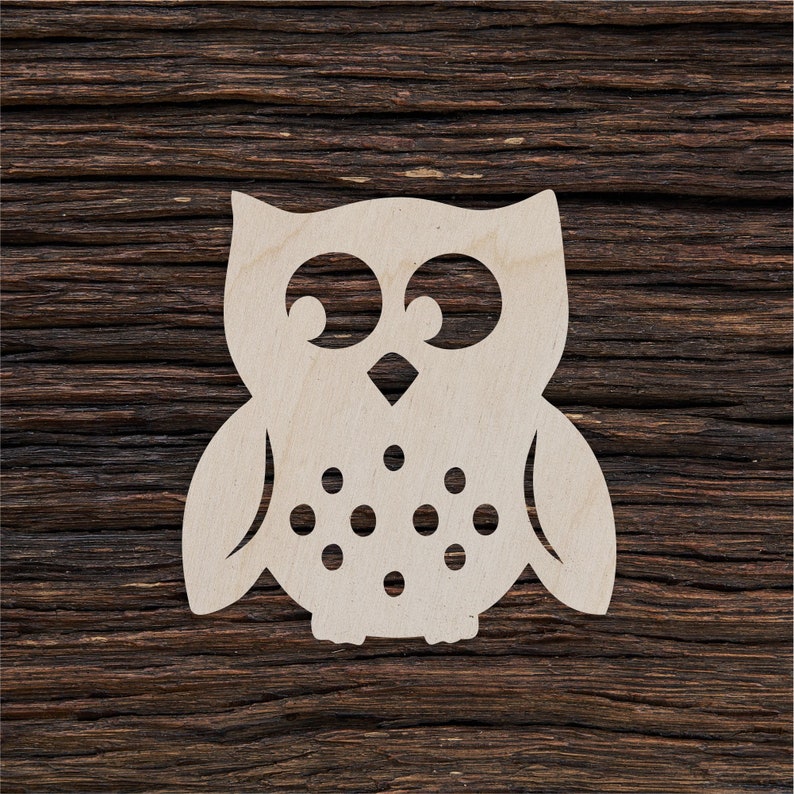 May include: A wooden cutout of an owl with large eyes and a simple design. The owl is painted white and has a brown wooden background.