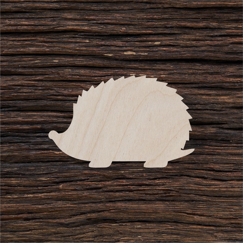 May include: A wooden cutout of a hedgehog, painted white, against a dark brown wood background.
