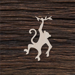 Puede incluir: Un recorte de madera blanco de un mono colgado de una rama. El mono está mirando hacia la derecha y tiene una cola larga.