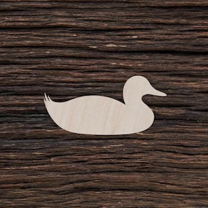 Op de afbeelding: Een witte houten uitsnede van een eend op een donkerbruine houten achtergrond.