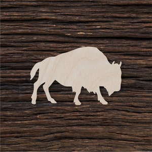 May include: A white wooden cutout of a bison silhouette on a dark brown wood background.