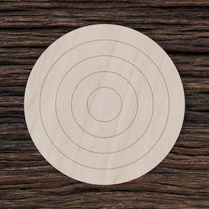 May include: A round wooden disc with concentric circles etched into the surface. The disc is light brown in color and has a smooth, polished finish.