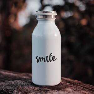 May include: White reusable water bottle with a silver lid and the word "smile" printed in black on the front.