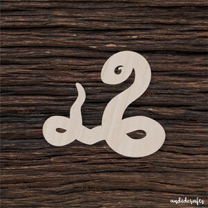 May include: A light-coloured wooden cutout in the shape of the Arabic word "Muhammad" against a dark wood grain background. The cutout features a stylized script with flowing lines and curves, showcasing the name in a decorative manner.