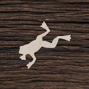 Könnte beinhalten: Ein weißer Holzausschnitt eines Frosches auf einem dunkelbraunen Holzgrund.