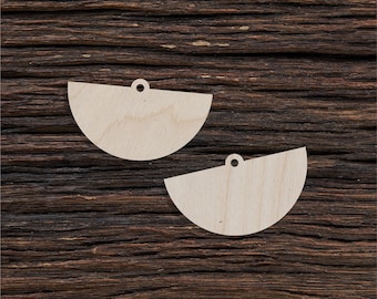 May include: Two unfinished wooden half-circle shapes with a hole at the top. The shapes are on a dark brown wooden surface.