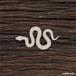 May include: A light-coloured wooden snake cutout, featuring a curved body and a pointed tail. The snake is positioned on a dark brown, textured wooden surface. The cutout is likely for crafting or decorative purposes.